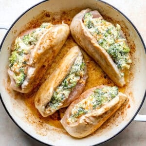Broccoli stuffed chicken breasts cooking in a pan.