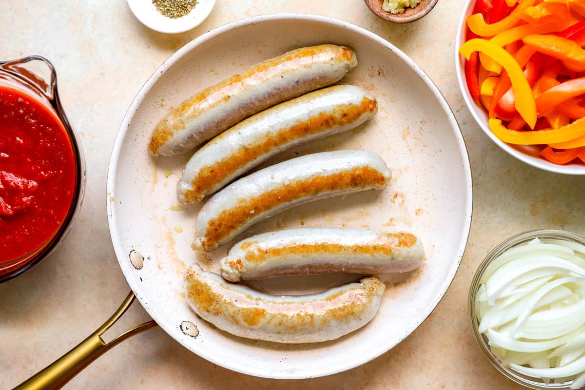 Italian chicken sausage cooking in a skillet.