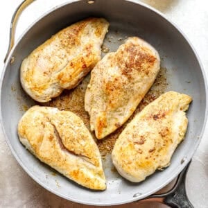 Browned chicken breasts in a pan.