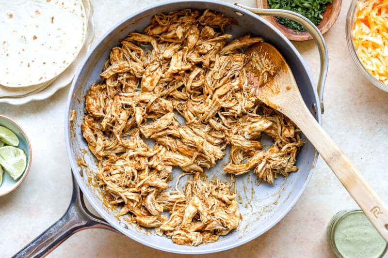 Cooking shredded chicken with taco seasoning.