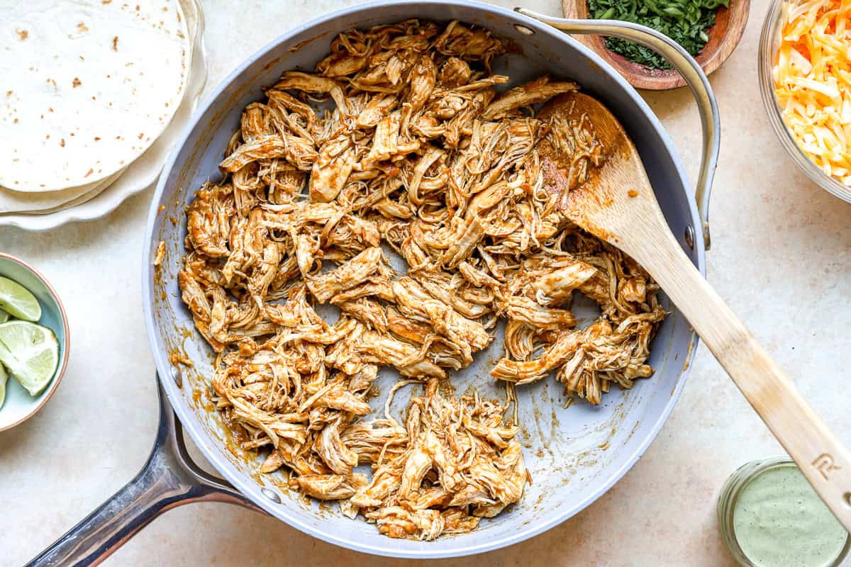 Cooking shredded chicken with taco seasoning.