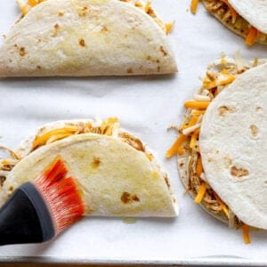 Brushing chicken tacos with oil.