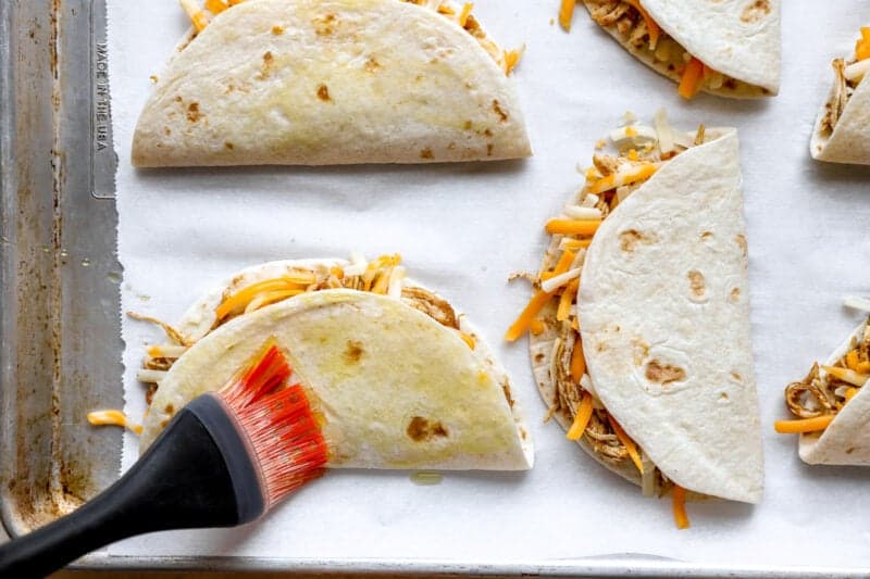 Brushing chicken tacos with oil.