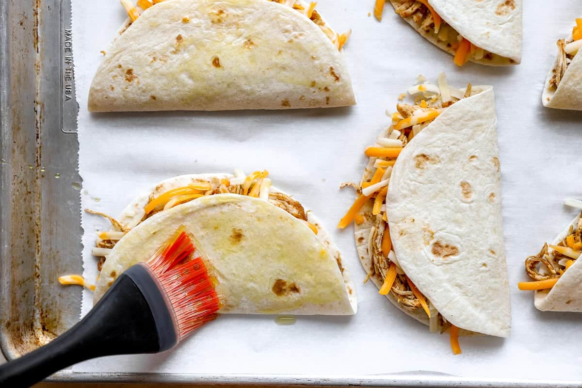 Brushing chicken tacos with oil.