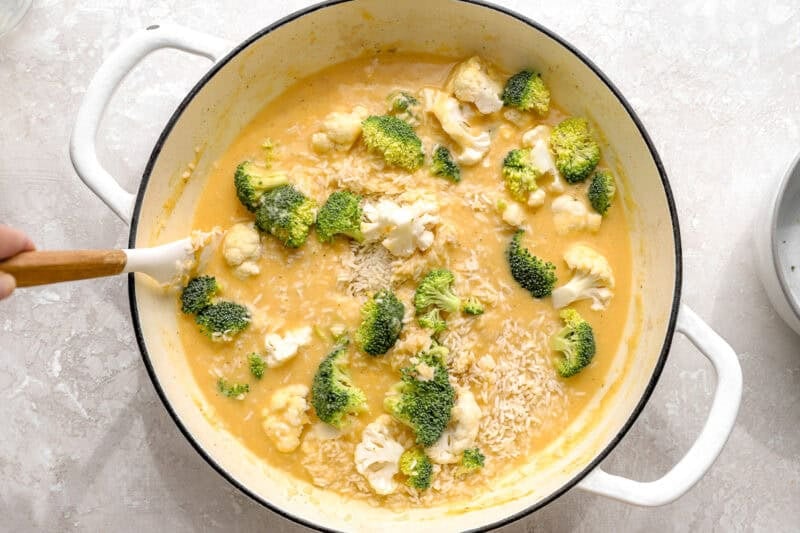 Stirring rice, broccoli, and cauliflower into cream of chicken mixture.