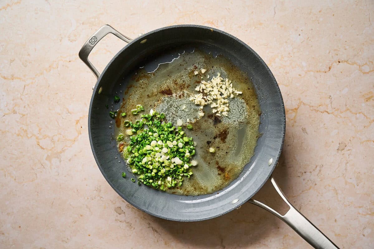 Sautéing garlic and green onion in a pan.