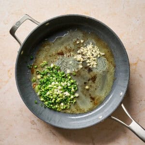 Sautéing garlic and green onion in a pan.