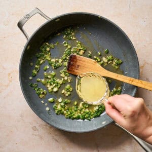 Adding broth to a pan to deglaze.