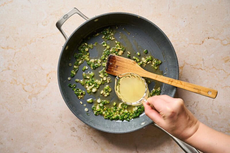 Adding broth to a pan to deglaze.