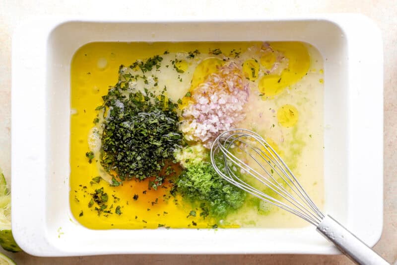 Combining mint, lime, rum, and other marinade ingredients in a dish.
