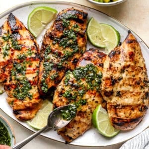 Drizzling cilantro lime mint sauce onto grilled chicken breast.