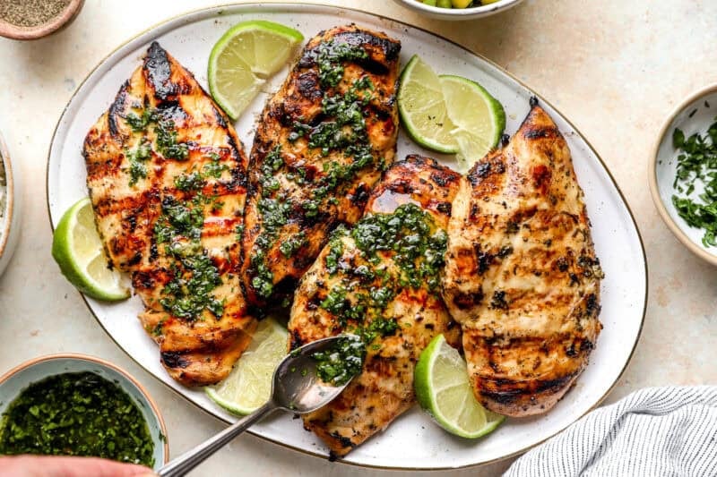 Drizzling cilantro lime mint sauce onto grilled chicken breast.