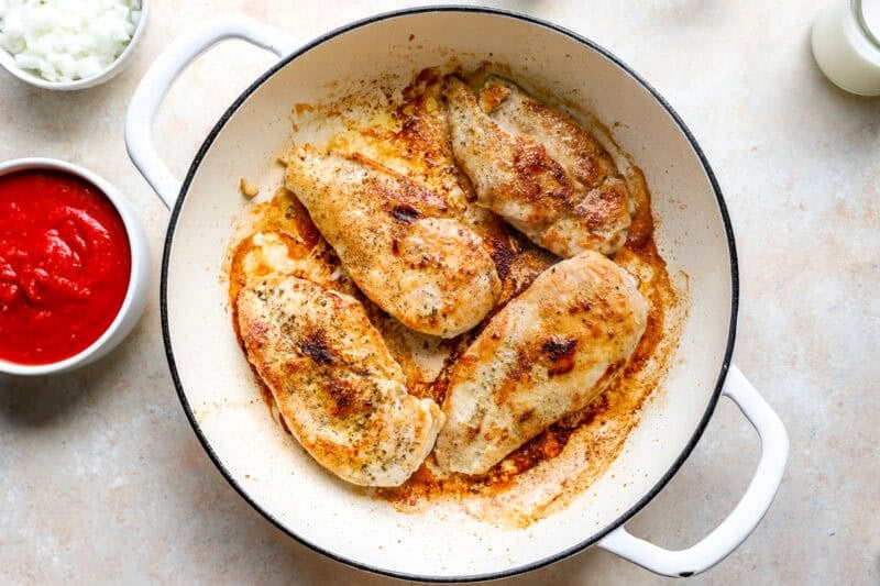 Seared chicken breasts in a pan.