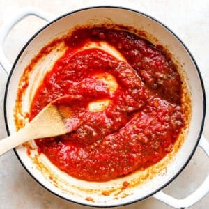 Stirring tomatoes into the pasta sauce.