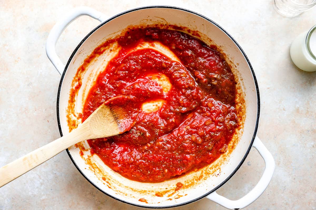 Stirring tomatoes into the pasta sauce.