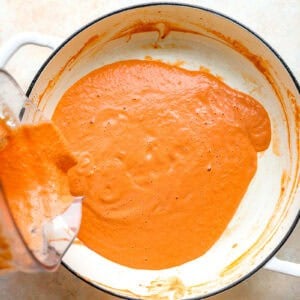 Pouring the creamy vodka sauce back into the pot.