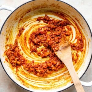 Cooking aromatics with curry paste in a skillet.