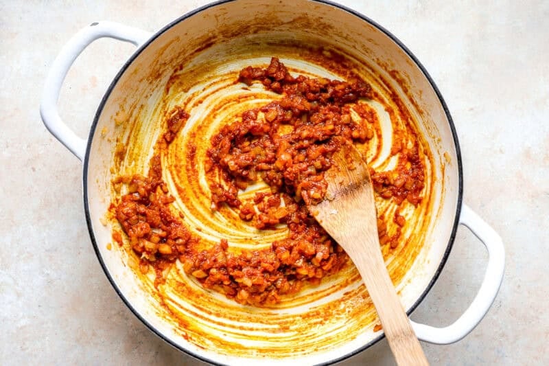 Cooking aromatics with curry paste in a skillet.