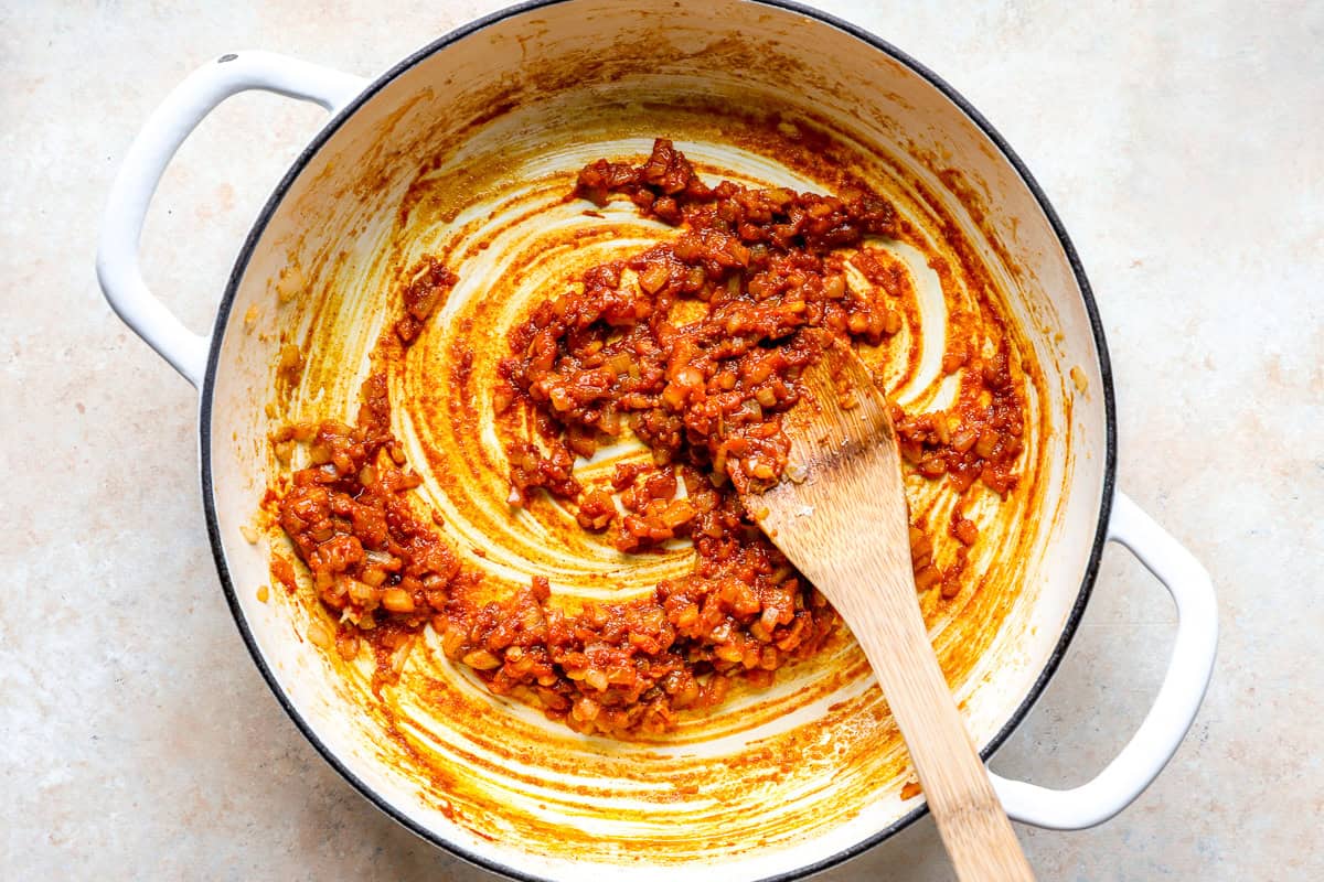 Cooking aromatics with curry paste in a skillet.