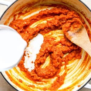 Adding coconut milk to a skillet.