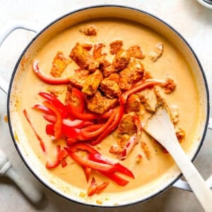 Chicken and pumpkin curry cooking in a skillet.