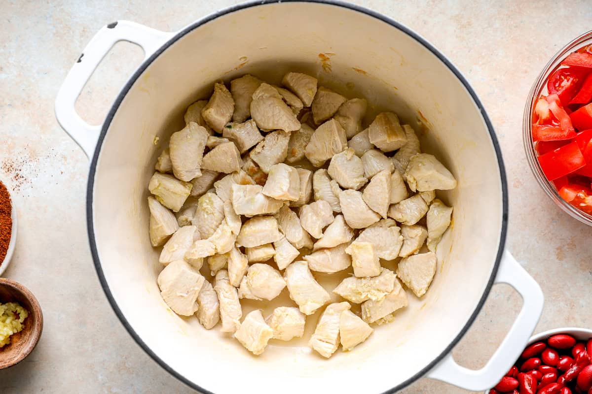 Cubes of chicken in a Dutch oven.