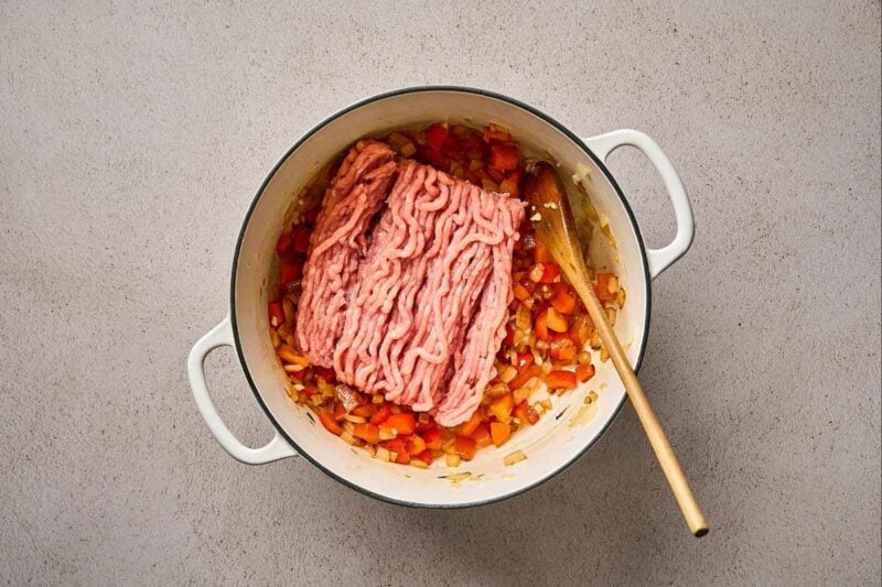Ground chicken added to a pot.