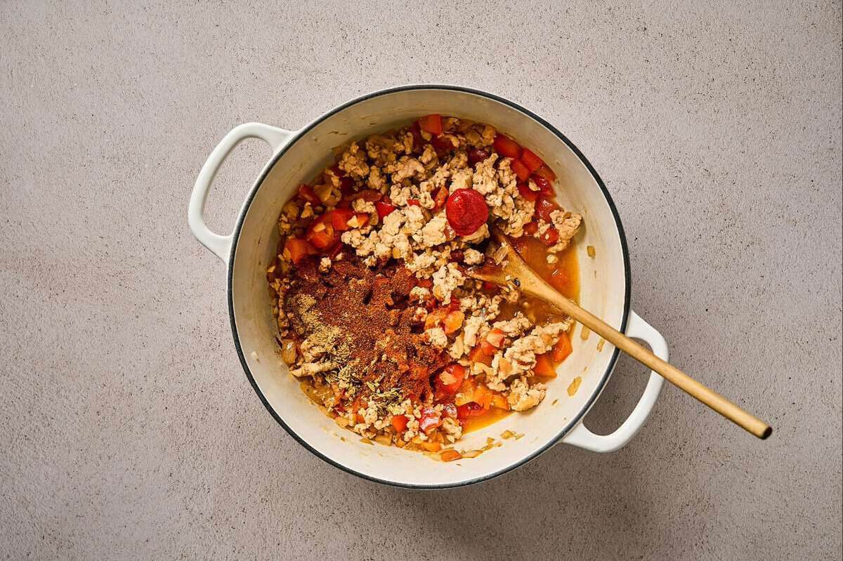 Cooking seasoned ground chicken and veggies in a pot.