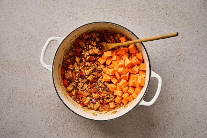 Cubed sweet potatoes added to a pot of ground chicken and veggies.