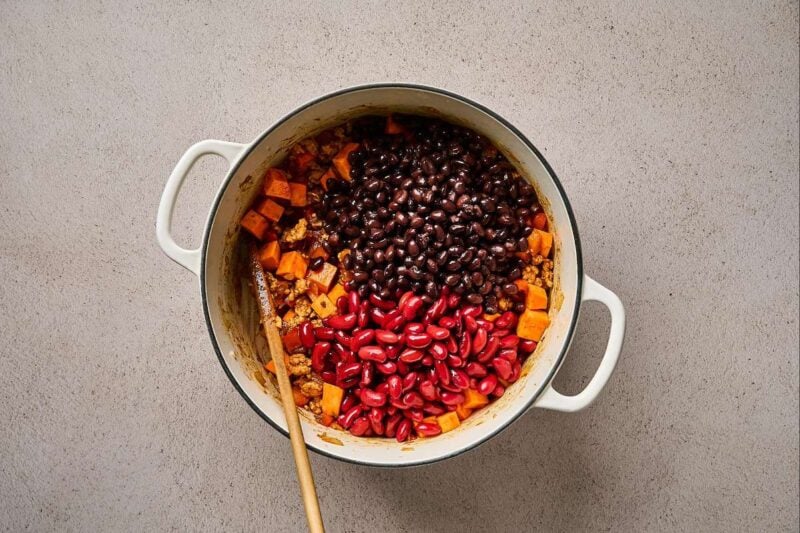 Beans added to a pot of sweet potatoes and ground chicken.