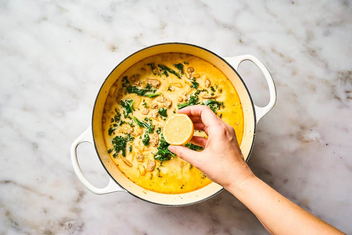 Finishing a pot of Zuppa Toscana soup with lemon juice.