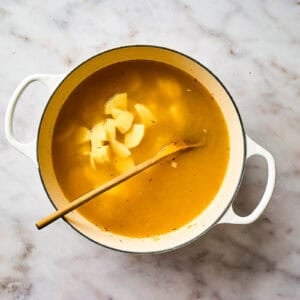 Potatoes added to soup broth in a pot.