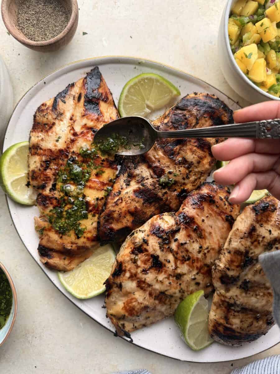 Drizzling cilantro mint sauce on top of grilled mojito chicken.