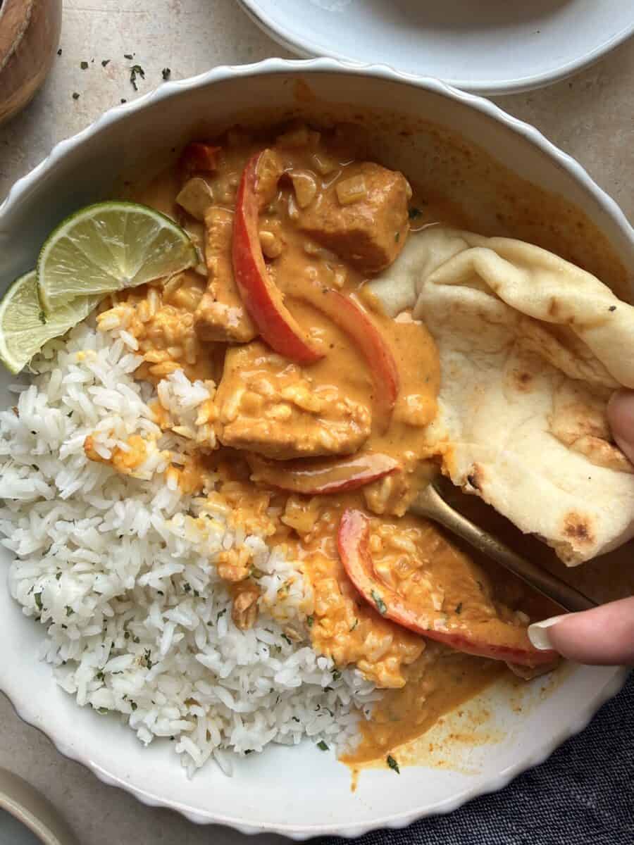 Eating a bowl of pumpkin chicken curry with rice and naan.