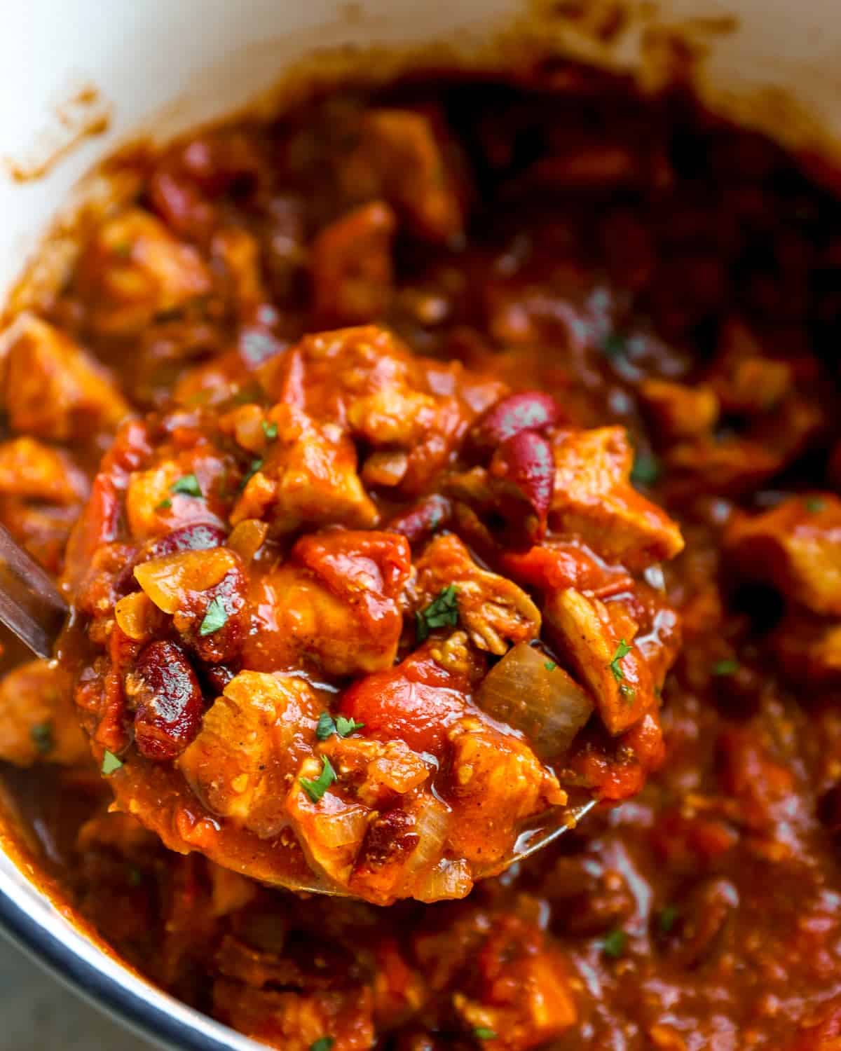 A ladle full of red chicken chili.