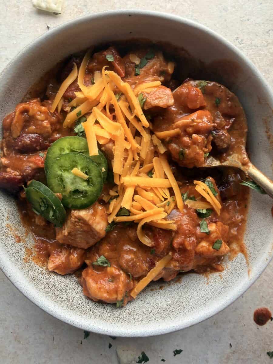 Eating a bowl of red bean chili with chunks of chicken.